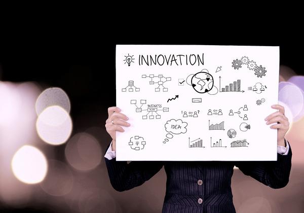 Person holding up white sign with the work Innovation and a number of small graphics