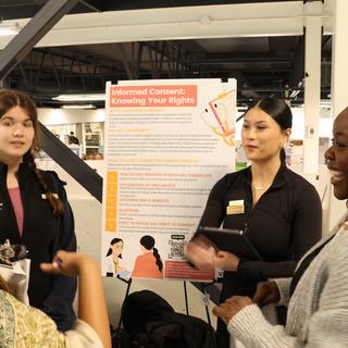 Group of students talking beside a poster at CREATE.