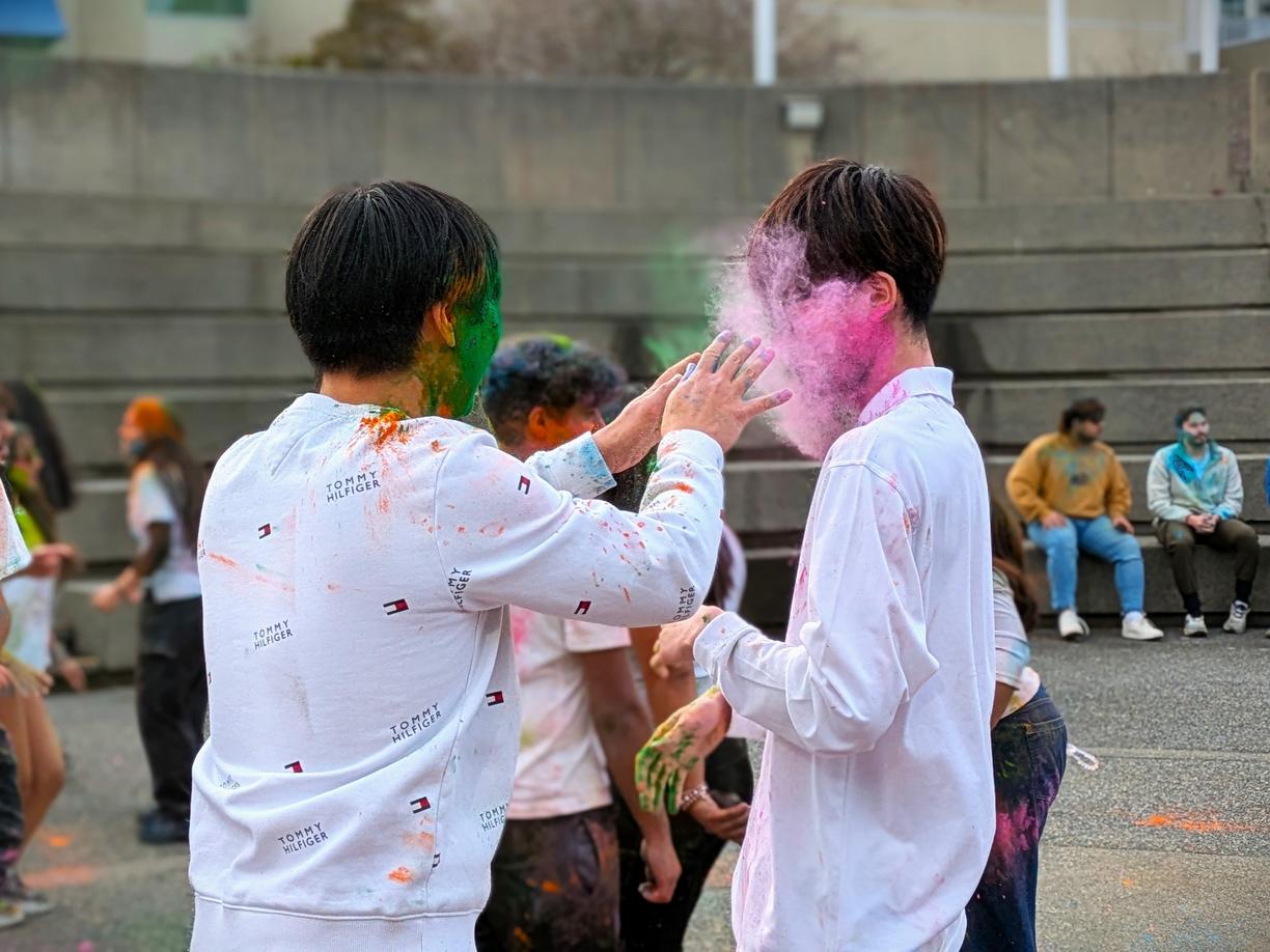 People wearing white whit faces covered with colored powder